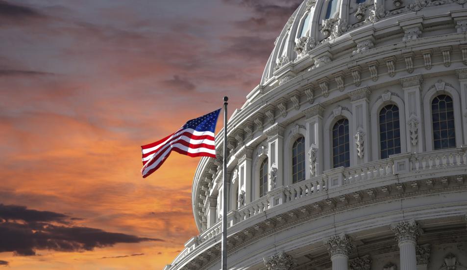Capitol Dome and U.S. Flag against dramatic sky
