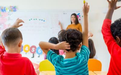 Children raising hands in classroom