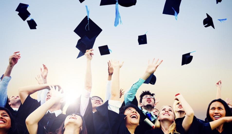 Graduates throwing mortar boards in the air